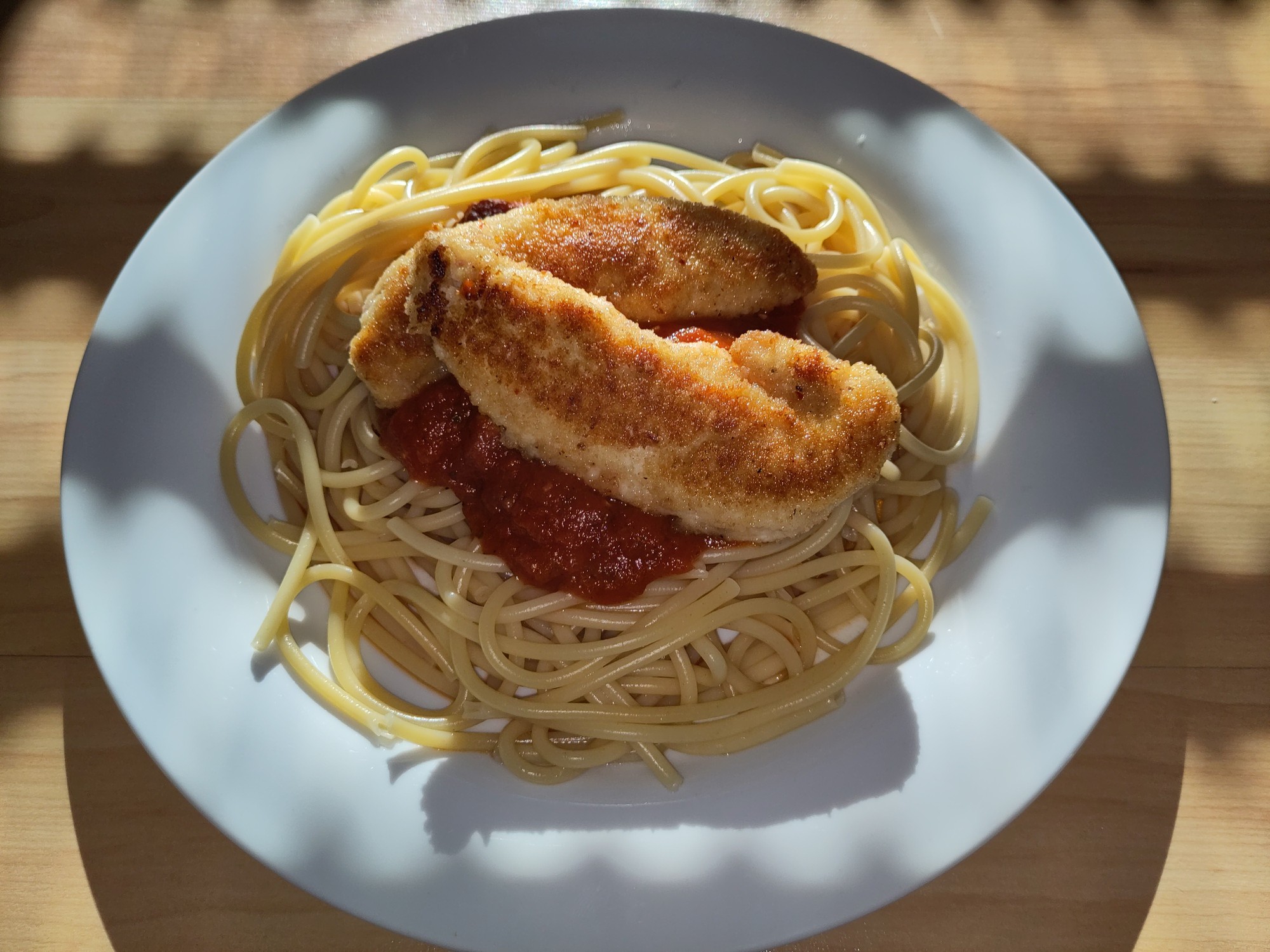 A plate of cooked maccheroni, tomato sauce and breaded chicken.